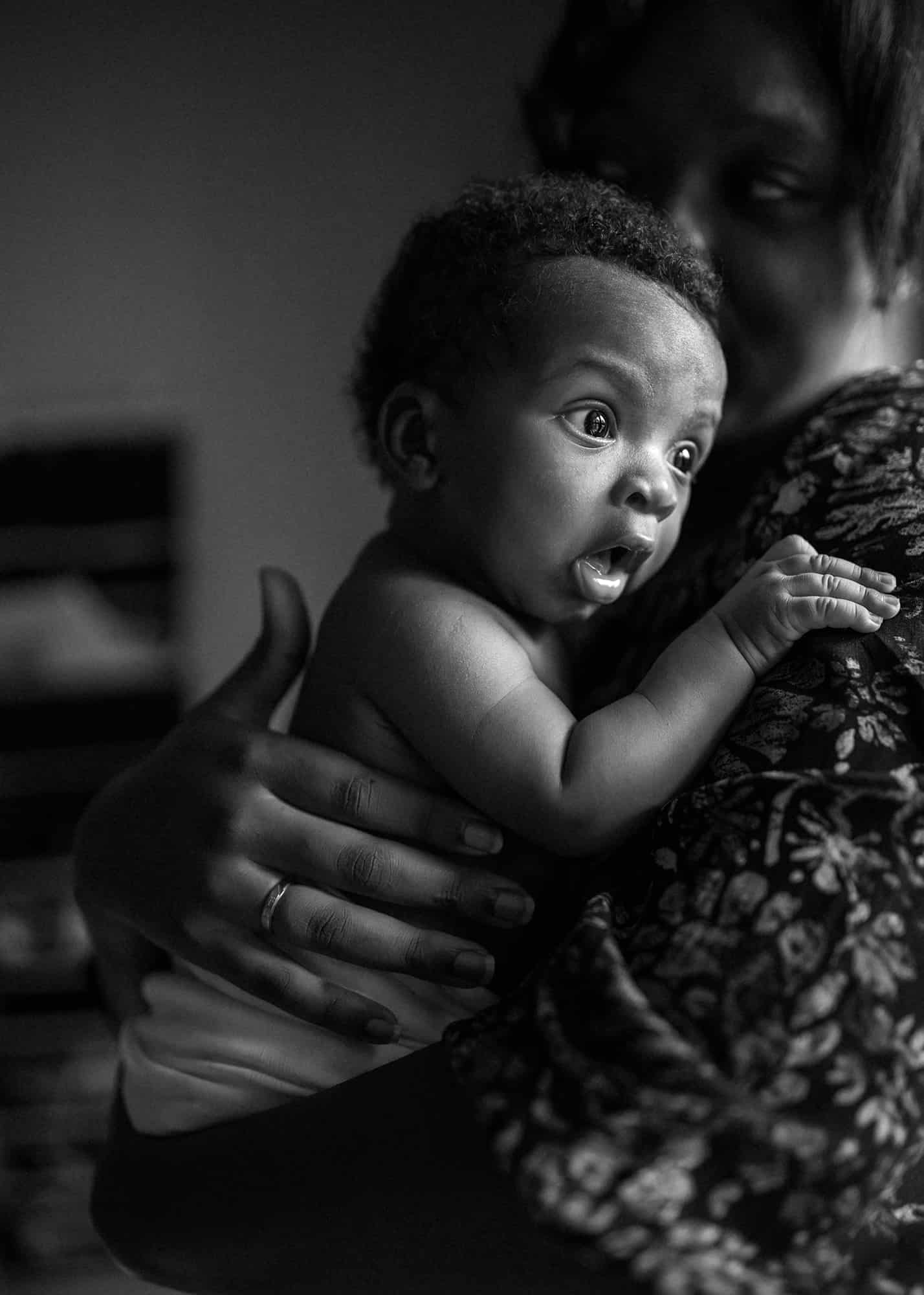 black and white newborn photographer orlando Florida - expressive baby looking out the window in his mom's arms