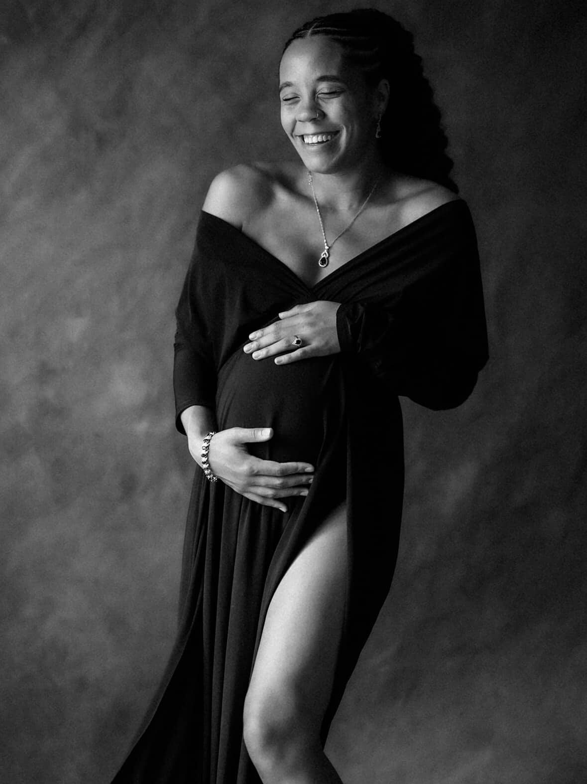pregnant woman wearing black dress laughing in front of an orlando maternity photographer
